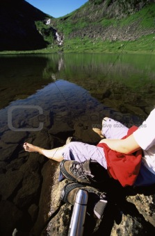 Young woman relaxing on rocks next to lake