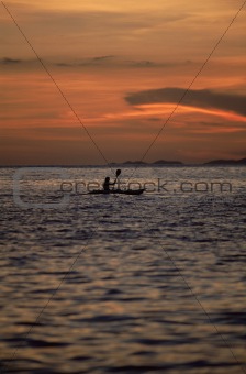 Silhouette of person kayaking at sea during sunset