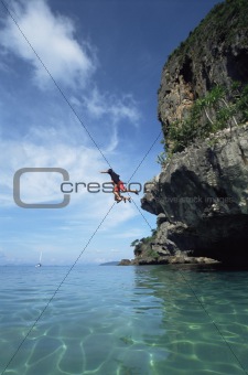 Couple jumping from cliffs into the sea