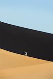 Woman walking across desert sand dunes