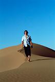Young man walking along sand dune