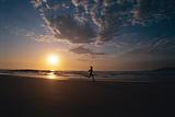 Person running along beach at sunset