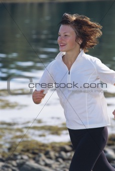 Young woman running along water's edge