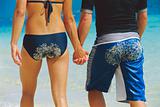 Rear view of young couple walking along beach with sandy bottoms