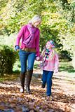 Mother and daughter walking along autumn path