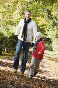 Father and son running along autumn path