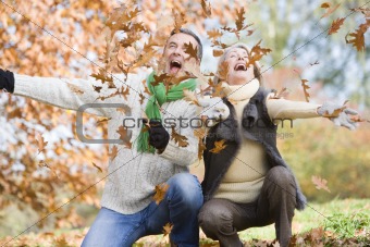 Senior couple throwing leaves in the air