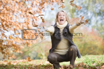Senior woman throwing leaves in the air