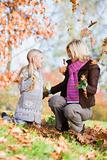Mother and daughter throwing leaves in the air