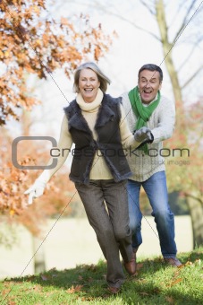 Senior man chasing woman through countryside