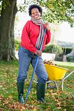 Mature woman collecting leaves in garden