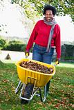 Mature woman collecting leaves in garden