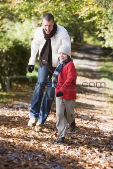 Father and son running along woodland path