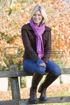 Young woman sitting on fence
