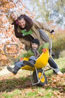 Father and mother pushing son in wheelbarrow
