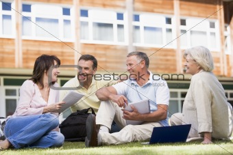 Adult students sitting on a campus lawn