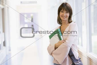 A woman with a backpack standing in a campus corridor