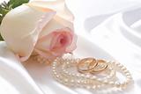 Rose, pearls and wedrings over white satin