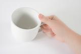 Hand holding white mug