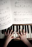 child's hands playing on a old piano 