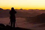 Silhouette of the photographer over a foggy mountain