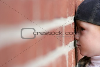 cute kid with nose squished against brick wall