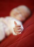 Detail of hand of sleeping baby on red background