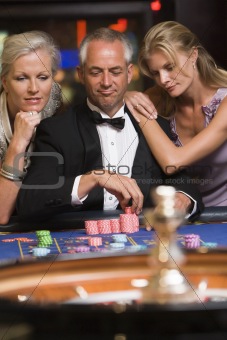 Man at roulette table with beautiful women
