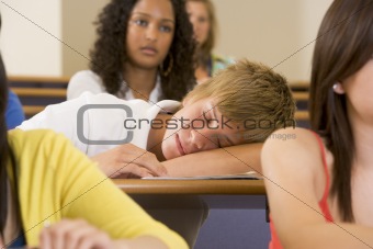 Male college student sleeping through a university lecture