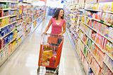 Woman pushing trolley along supermarket aisle