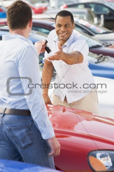 Man collecting new car from salesman