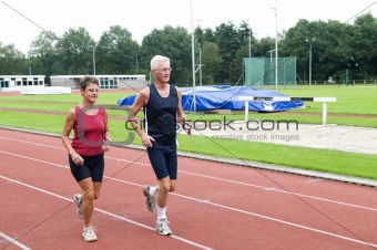 Senior Couple Running On A Track