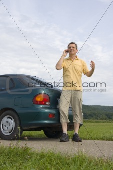 Man with mobile phone beside his car