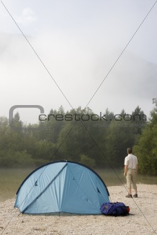 Backpacker standing beside his tent