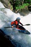 Young woman kayaking down waterfall