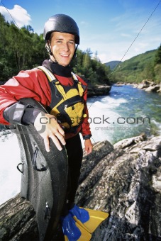 Man standing with raft beside river