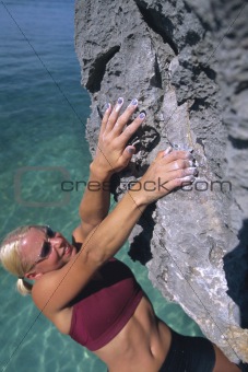 A young woman climbing up a rock face
