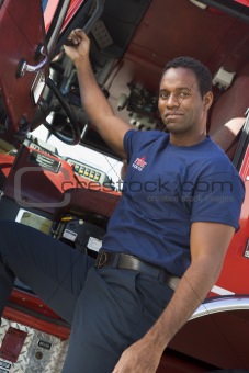 A firefighter standing by the cab of a fire engine