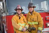 Portrait of two firefighters by a fire engine