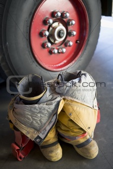 Empty firefighter\'s boots and uniform next to fire engine
