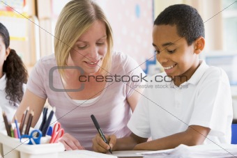 A schoolboy sitting with his teacher in class