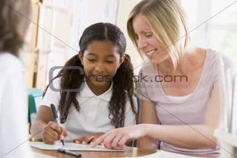A schoolgirl sitting with her teacher in class