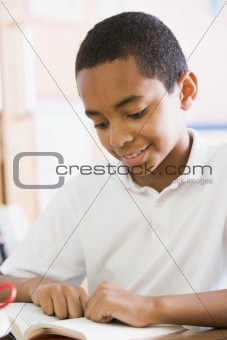 Schoolboy reading a book in class