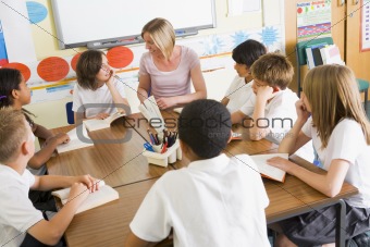 Schoolchildren and their teacher reading books in class