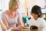 A schoolboy and his teacher reading a book in class