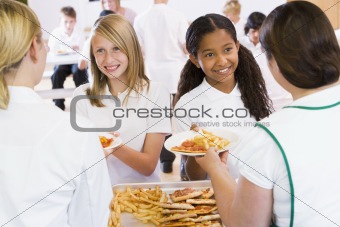 Lunchladies serving plates of lunch in school cafeteria