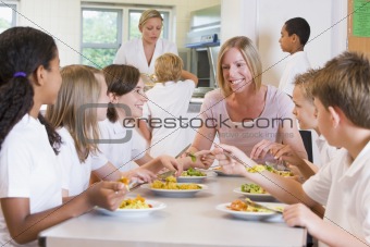 Teacher and schoolchildren enjoying their lunch in a school cafe