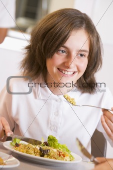 Schoolgirl enjoying her lunch in a school cafeteria