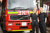 Portrait of two female firefighters standing by a fire engine