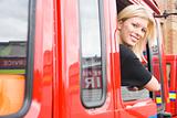 Female firefighter sitting in the cab of a fire engine